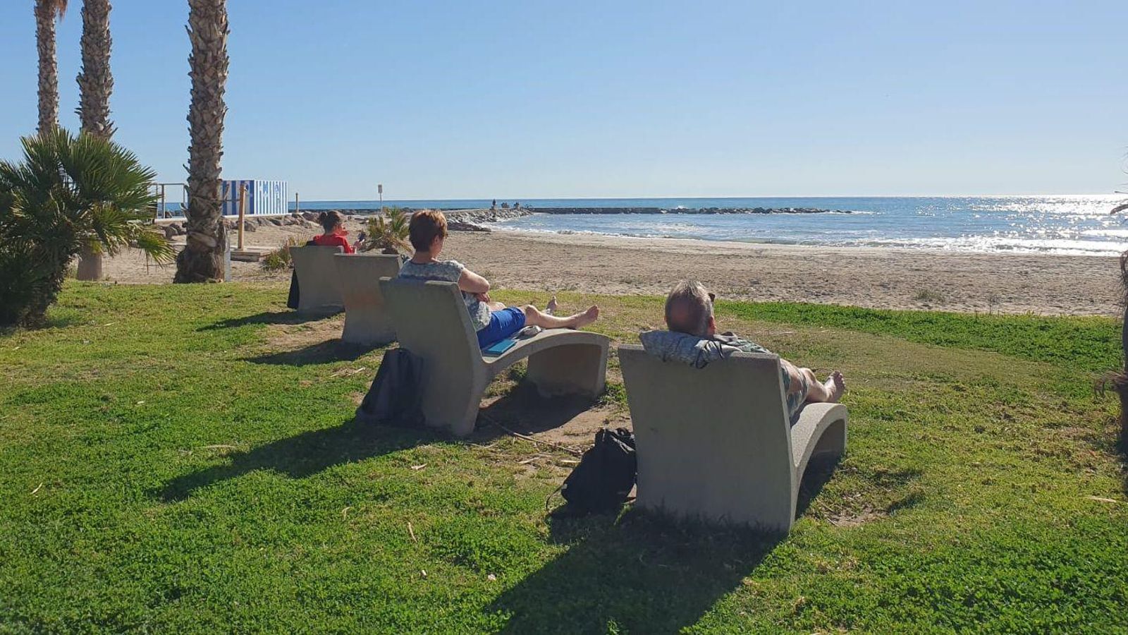 Diverses persones prenen el sol en un jardí situat vora mar a Benicàssim