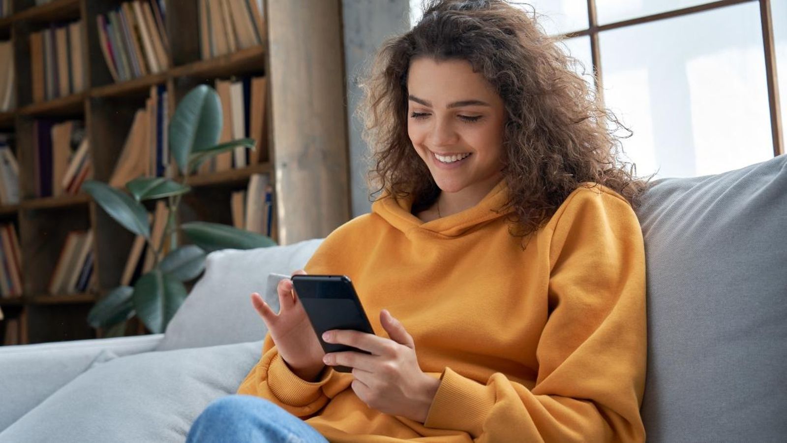 Una xica mira el seu telèfon mòbil al sofà