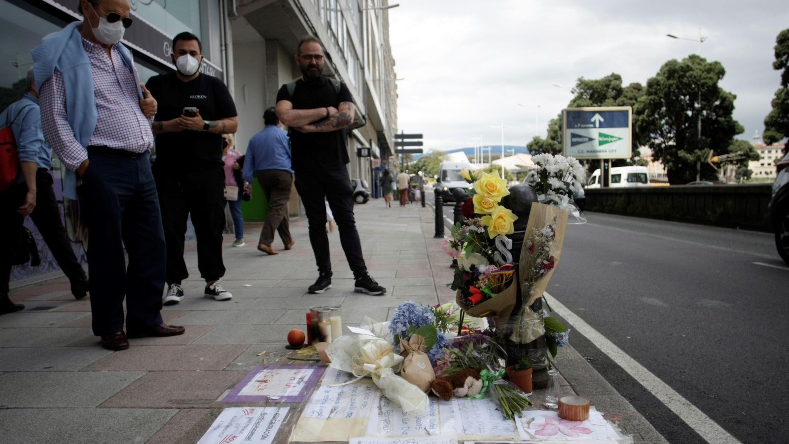 Diversos vianants observen l'altar improvisat, amb flors i missatges, que s'ha creat al punt on van matar Samuel