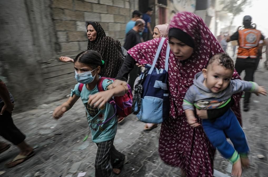 Una dona busca recer amb els fills durant un atac aeri a Gaza Una dona busca recer amb els fills durant un atac aeri a Gaza