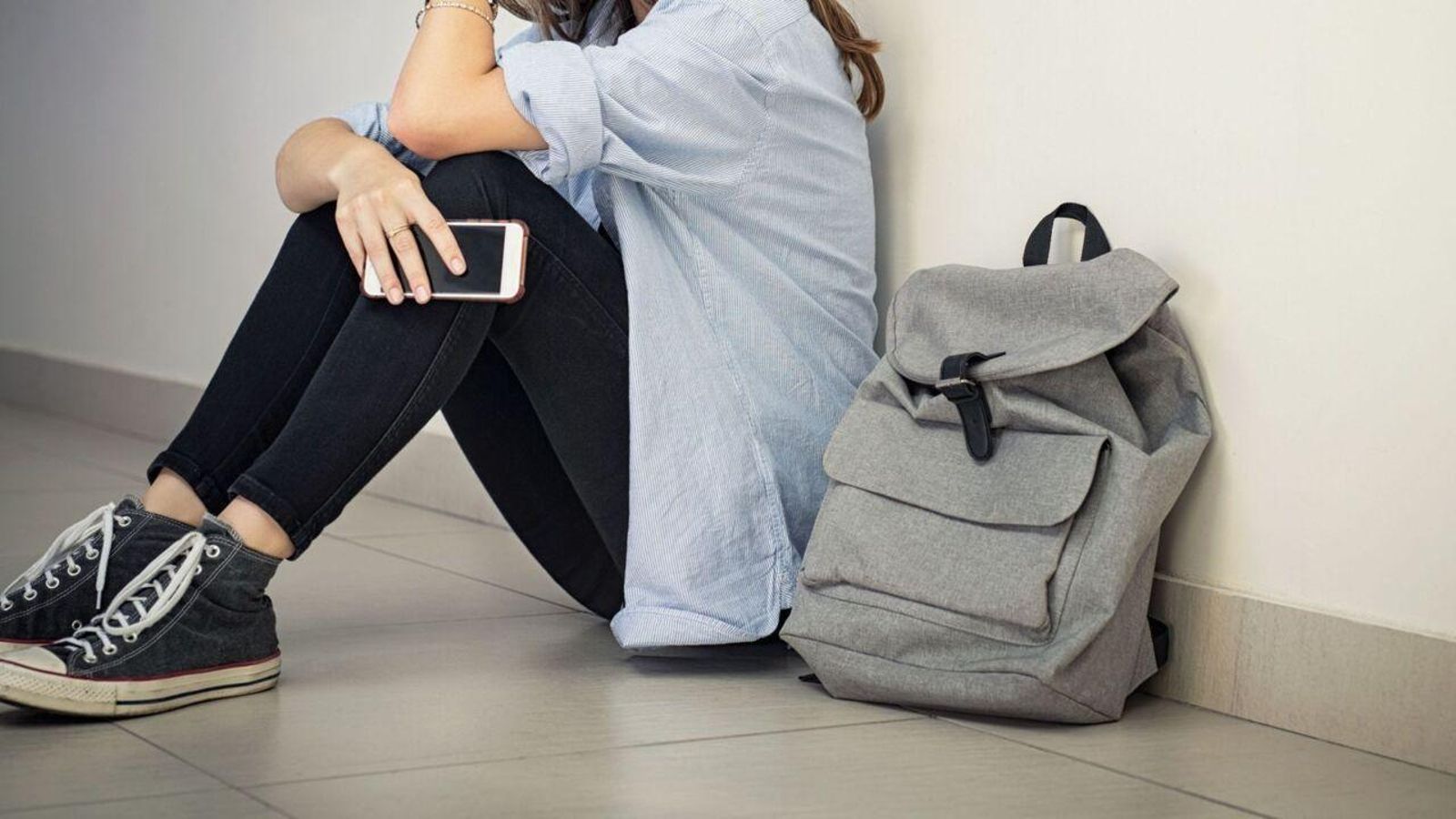 Una adolescent asseguda amb un telèfon mòbil