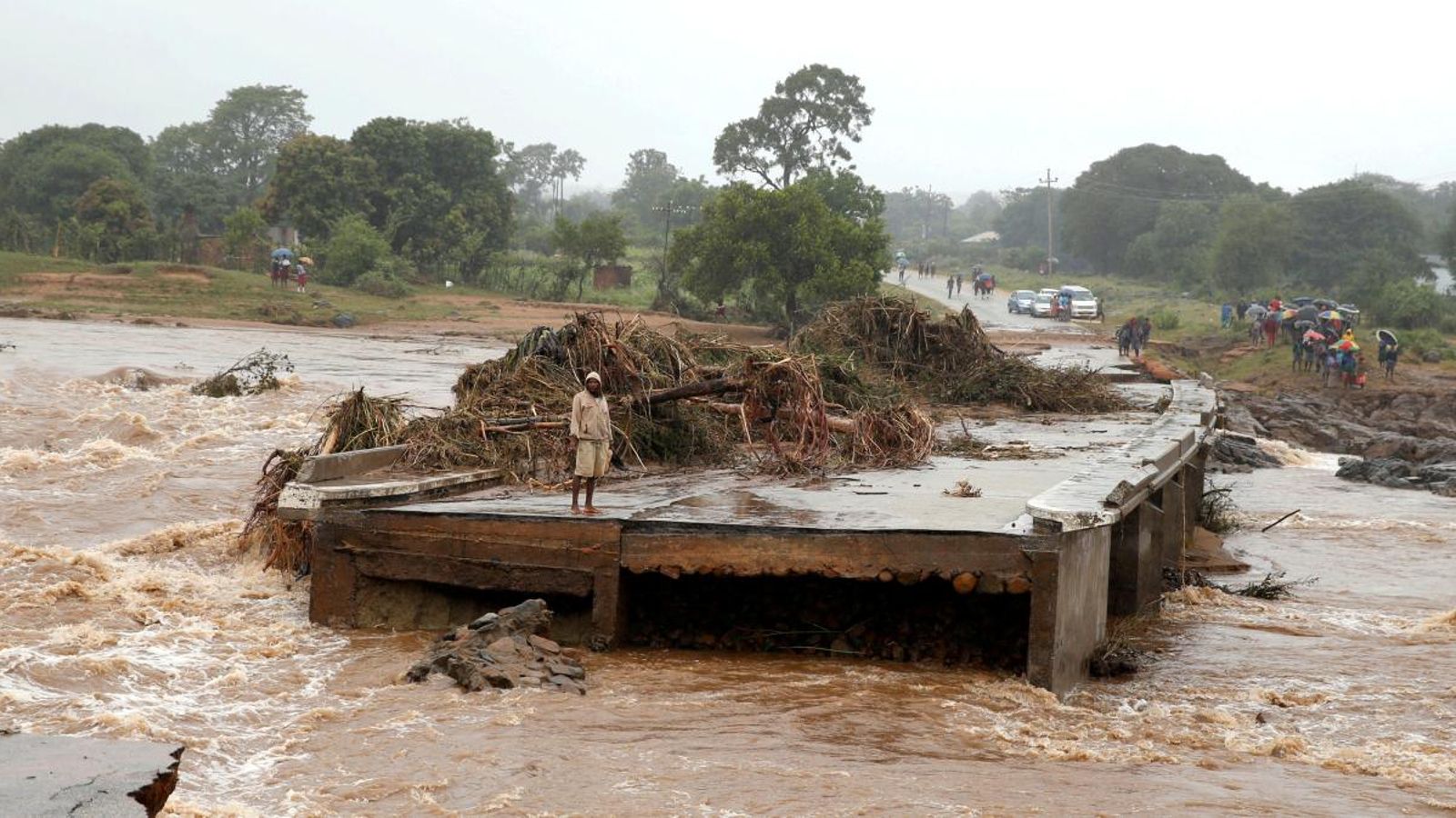 Un home mira un pont arrasat al llarg del riu Umvumvu després del pas del cicló Idai.