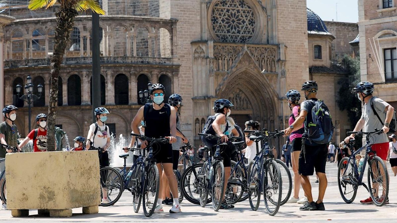 Un grup de turistes en bicicleta i mascareta pel centre de la ciutat de València