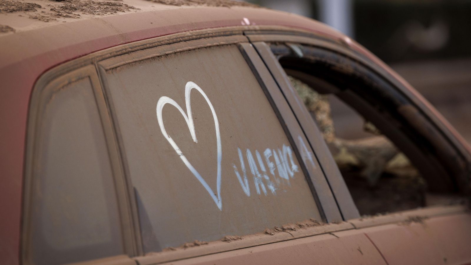 Un voluntari ha pintat un cor sobre un vehicle afectat per la DANA, a Paiporta