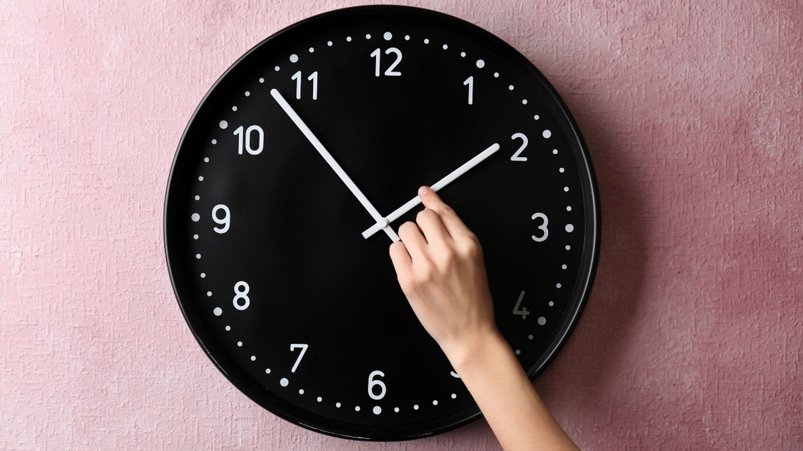 Una persona canvia l'hora d'un rellotge