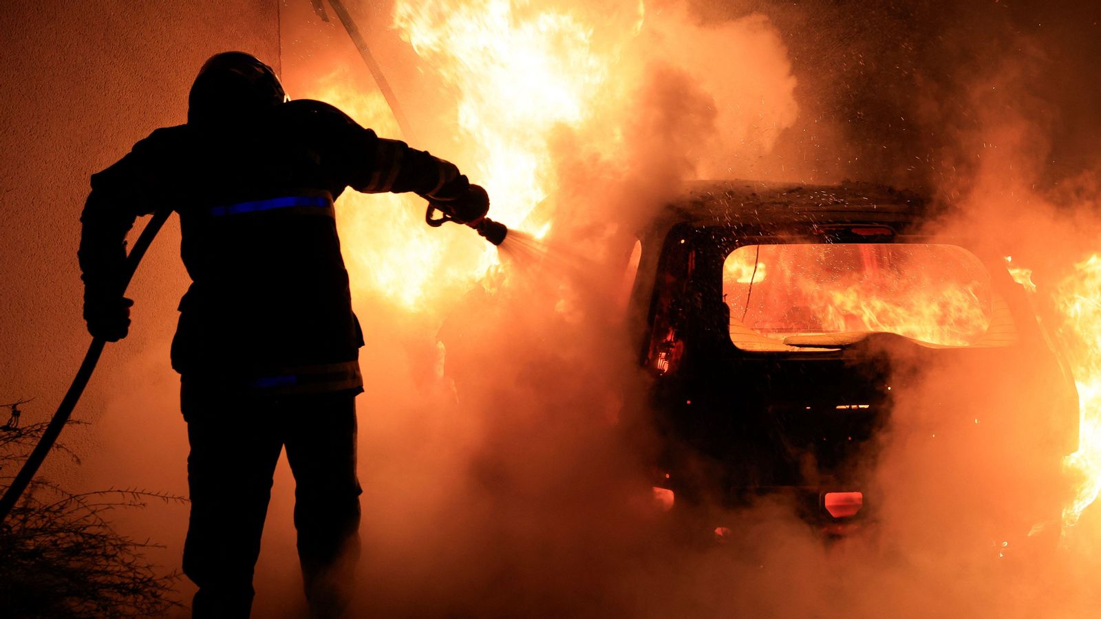 Un bomber tracta d'apagar un cotxe que els manifestants van botar foc durant una matinada de la setmana passada