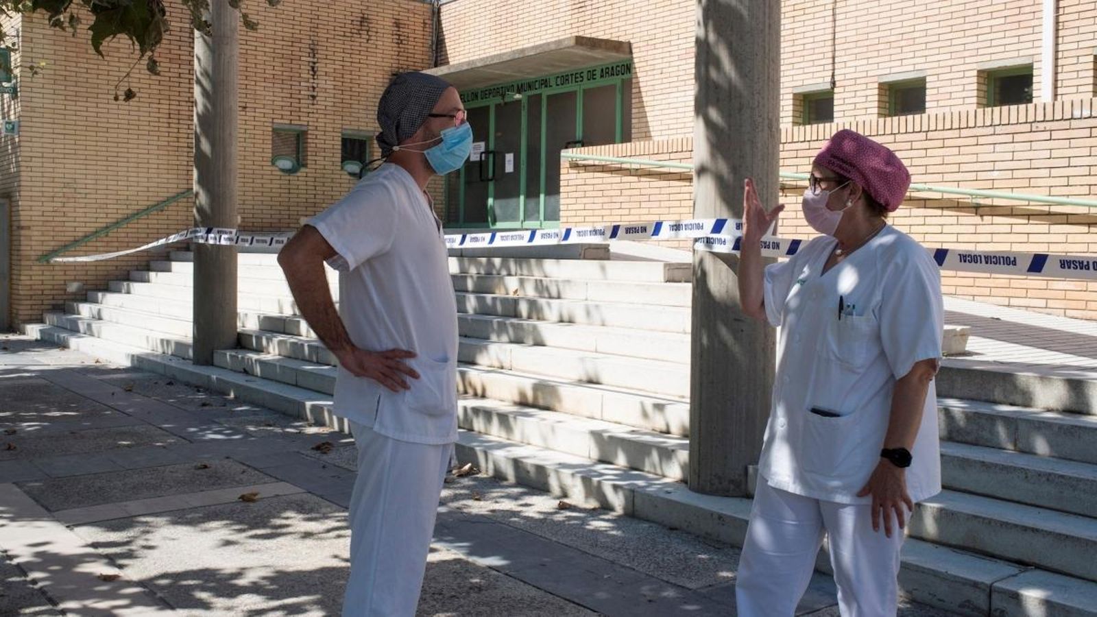 Dos sanitaris conversen en els voltants del poliesportiu de Fraga, Osca  on es troben alguns malalts amb coronavirus que no tenen allotjament o no poden mantindre la distància social a causa del virus