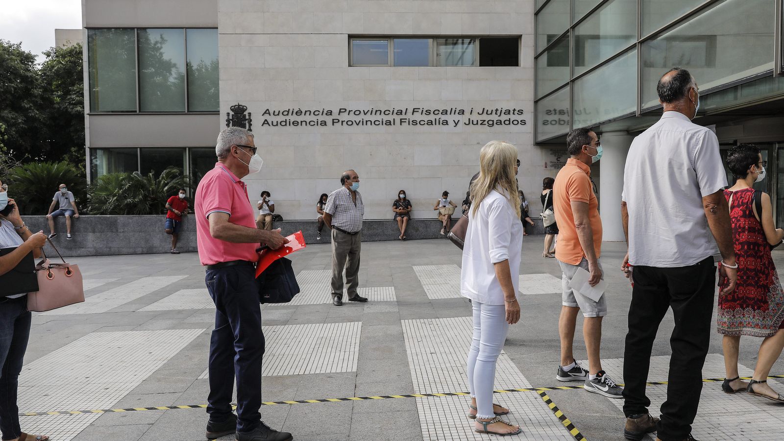 Un grup de persones, en filera, espera per a accedir a la Ciutat de la Justícia de València en una imatge d'arxiu