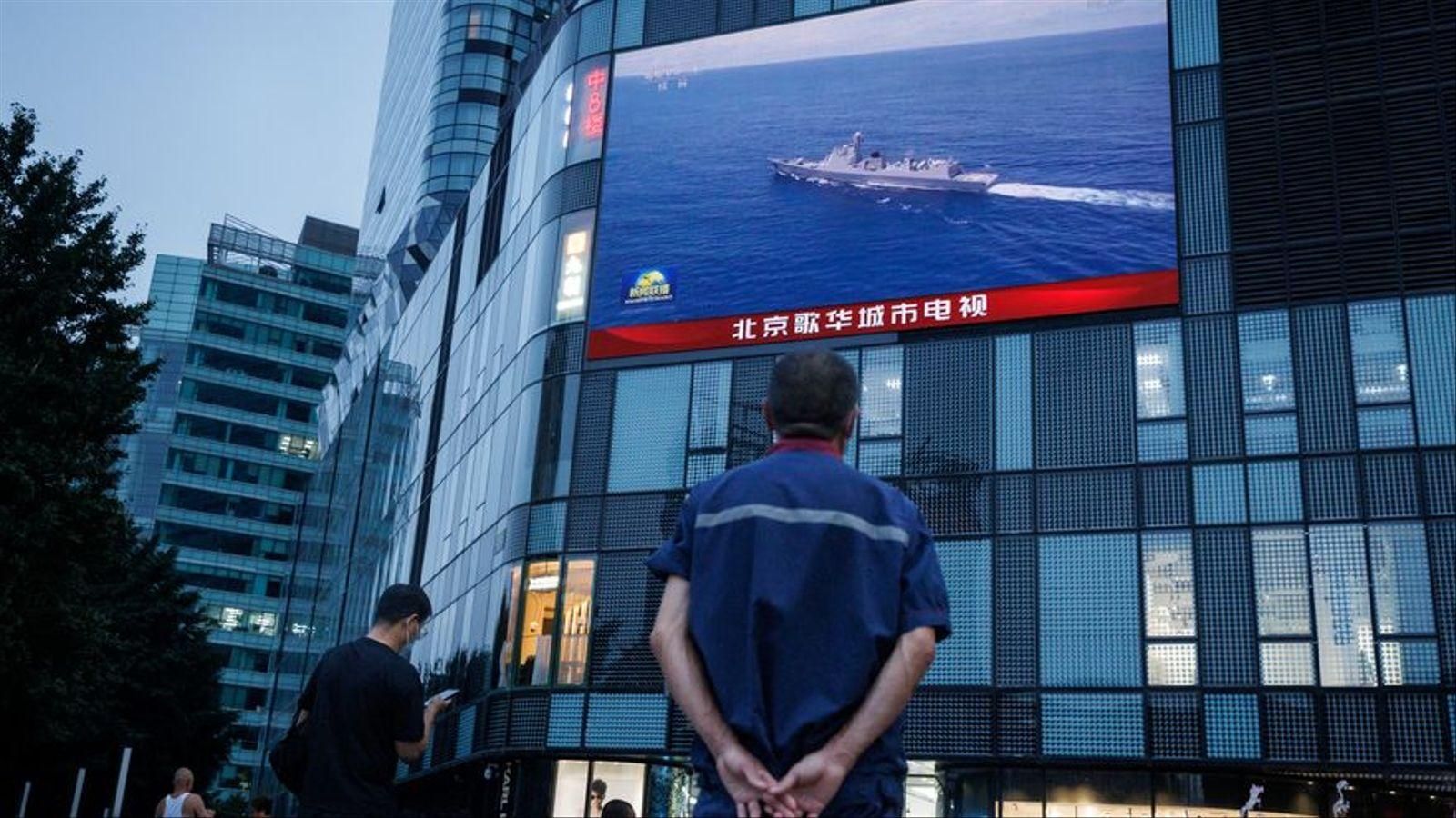Un home segueix per una pantalla a Pequín les operacions militars xineses prop de Taiwan