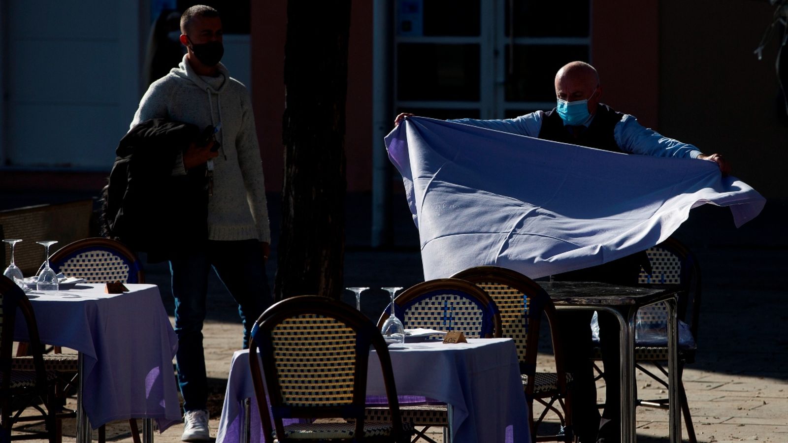 Un cambrer estén un mantel sobre la taula d'una terrassa a Catalunya, autonomia que aquest dilluns ha començat la desescalada