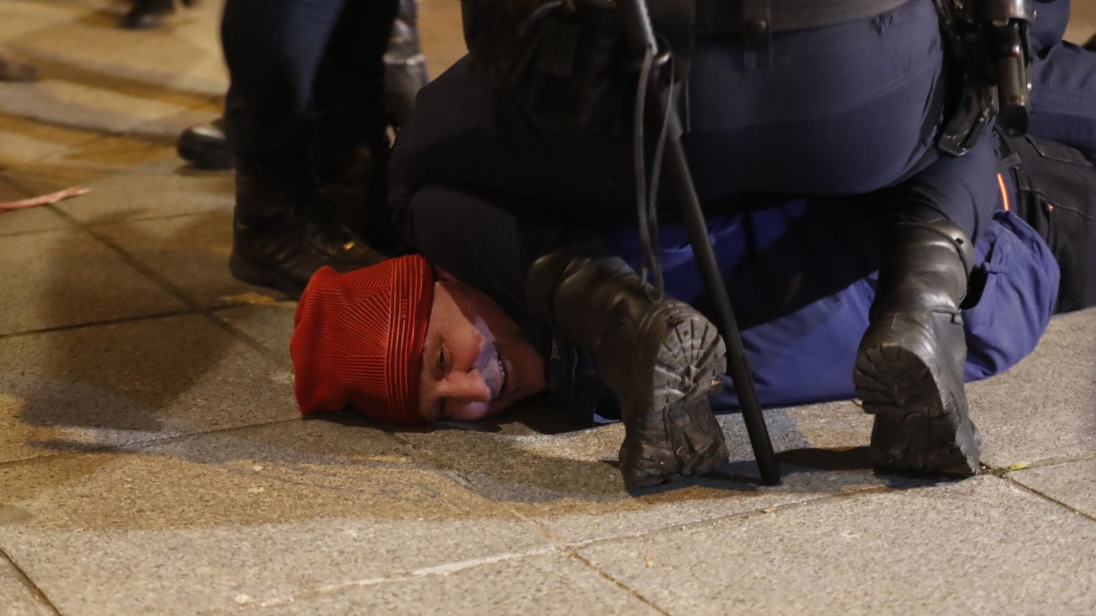 Agents etenen a una persona durant la concentració d'aquest dilluns enfront de la seu del PSOE al carrer Ferraz, a Madrid