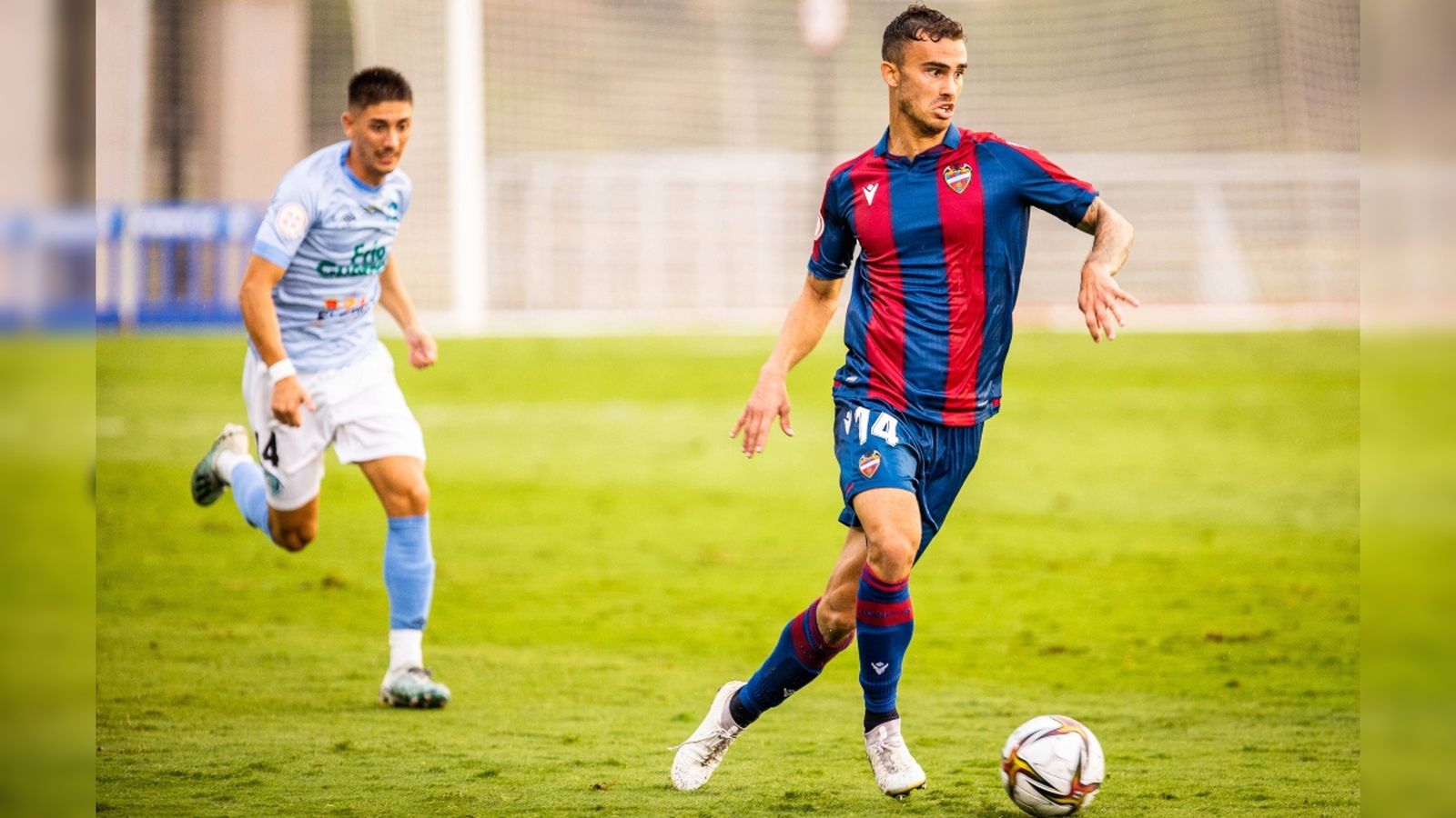 El jugador del Llevant Leal condueix el baló perseguit per un jugador de El Ejido