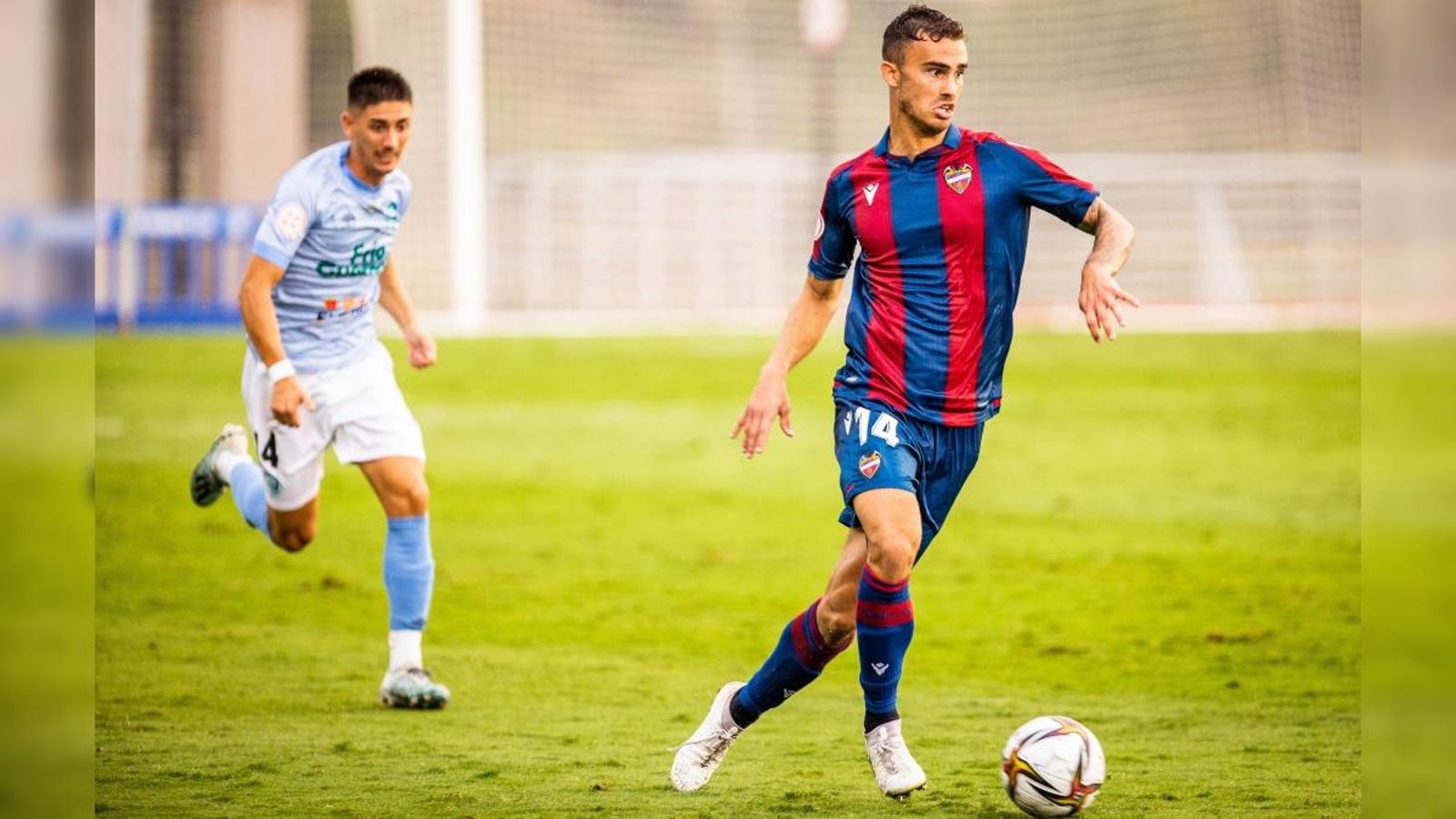 El jugador del Llevant Leal condueix el baló perseguit per un jugador de El Ejido