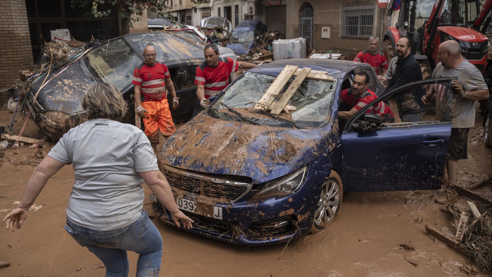 Un grup de veïns d'Aldaia i efectius d'emergències retiren uns vehicles arrosegats per la riuada al municipi