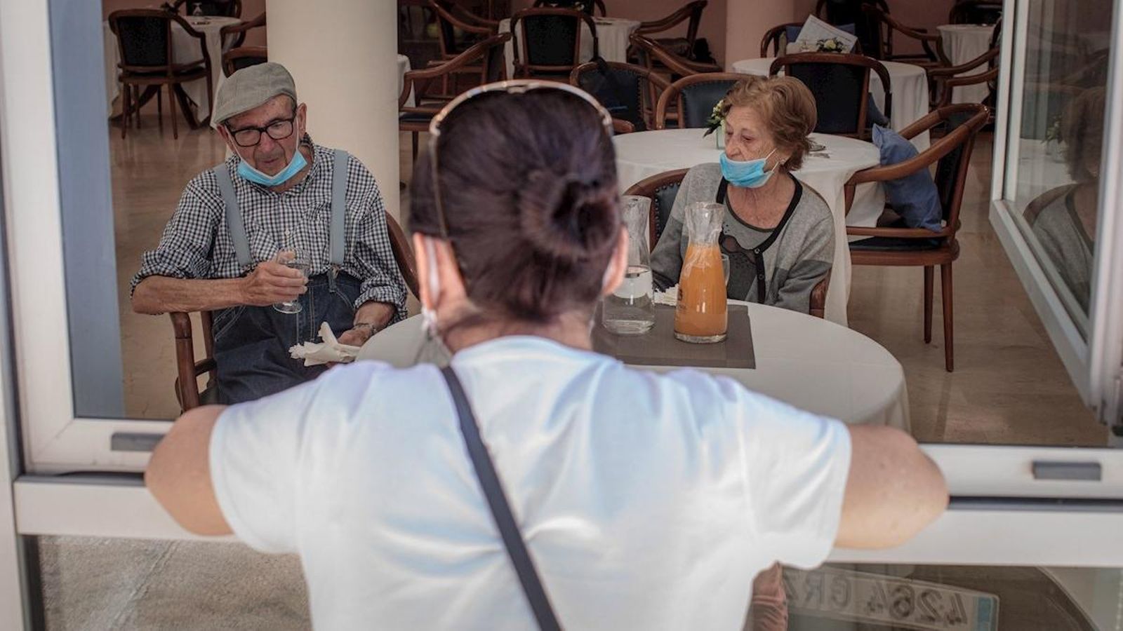 Una persona conversa amb els seus pares a través d'una finestra habilitada en la residència de majors Ballesol Patacona, a València