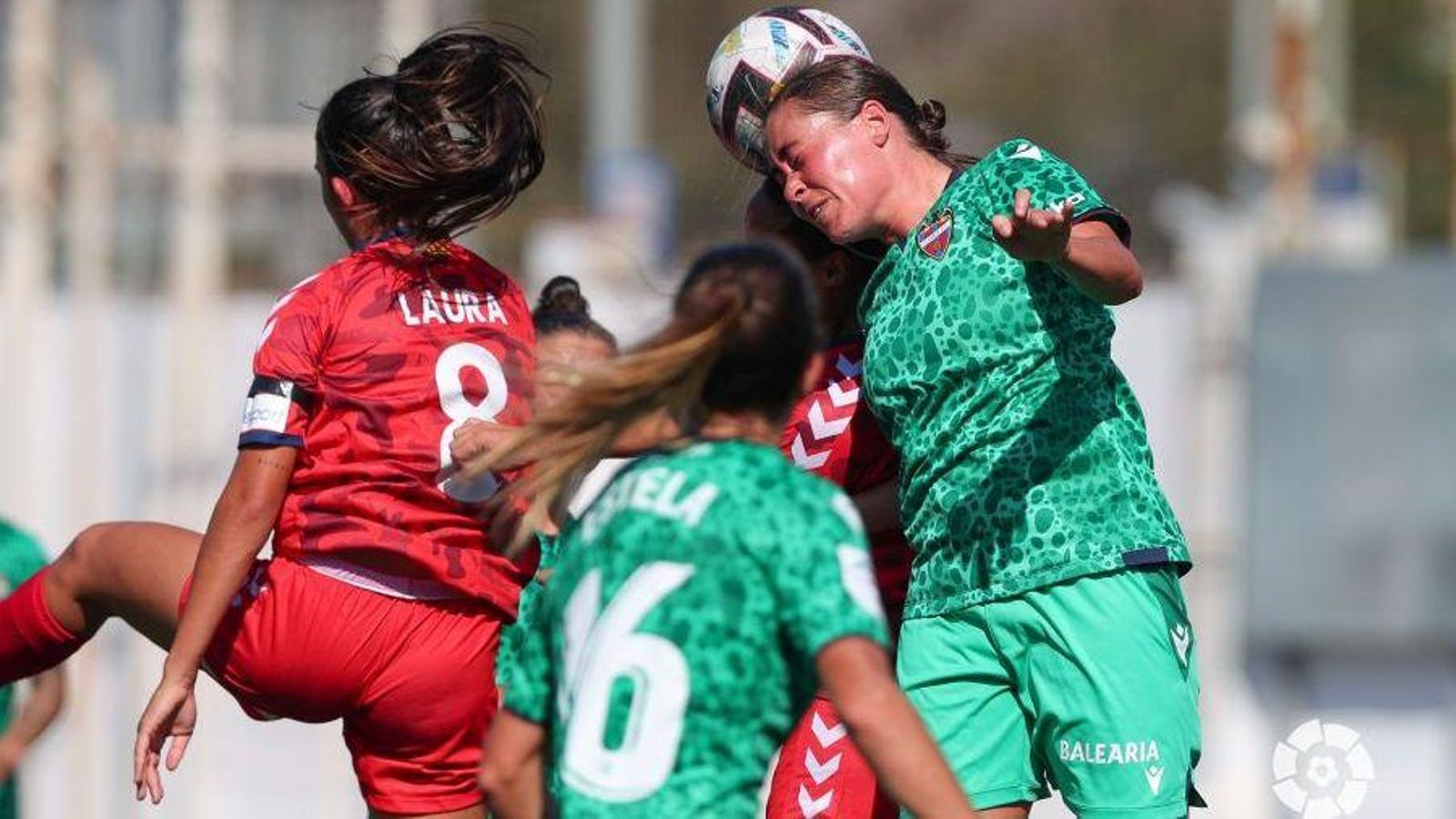 Dues futbolistes lluiten per una pilota dividida Dues futbolistes lluiten per una pilota dividida