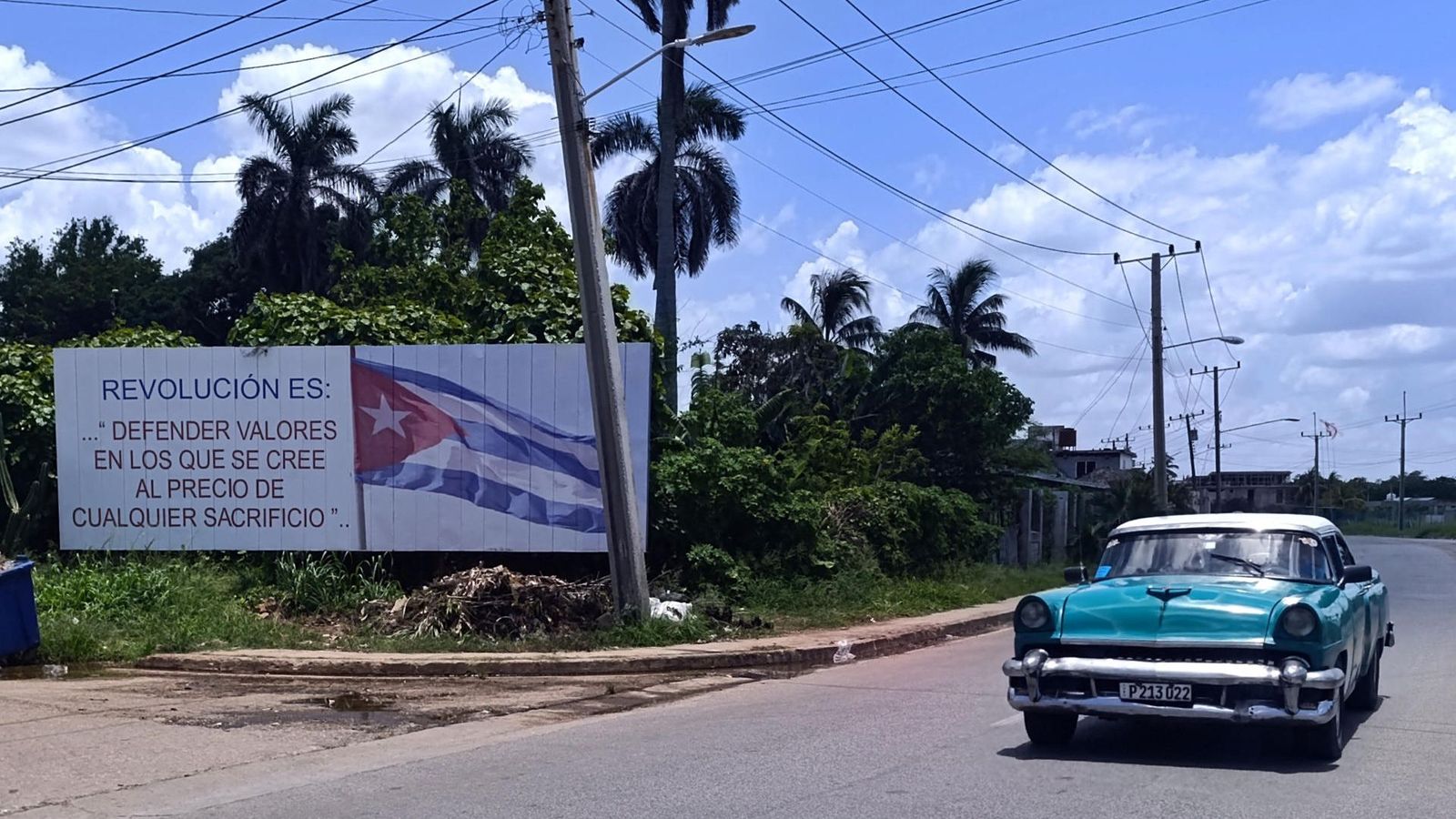 Un turisme passa davant d’un cartell de l’Habana amb una consigna revolucionària