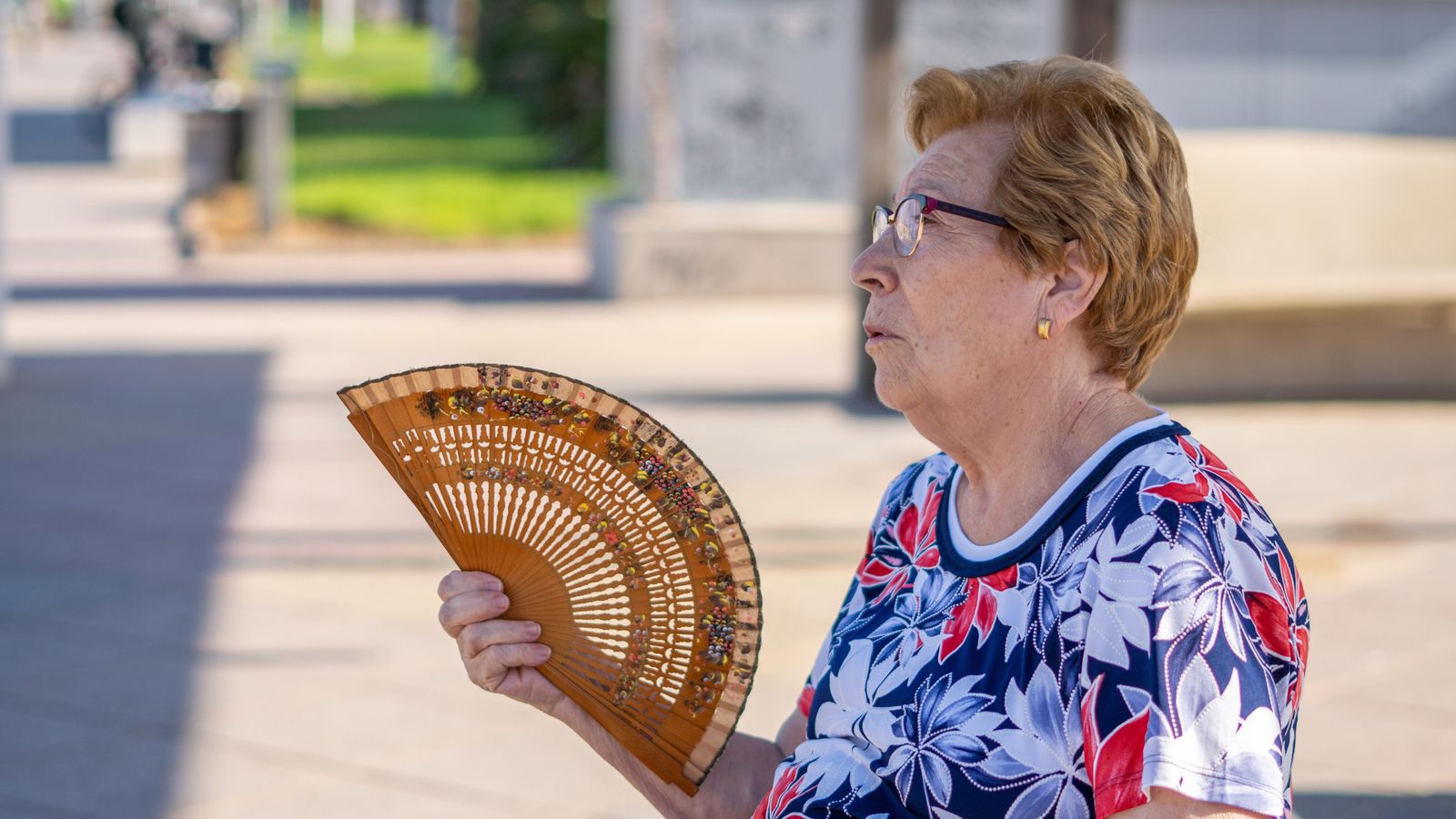 Una dona combat la calor amb un ventall Una dona combat la calor amb un ventall