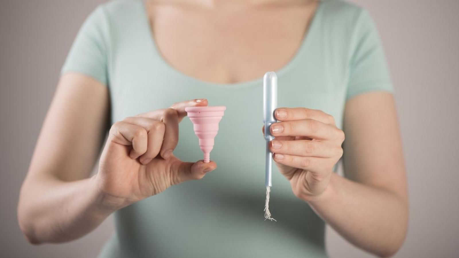 Una dona sosté un tampó i una copa menstrual