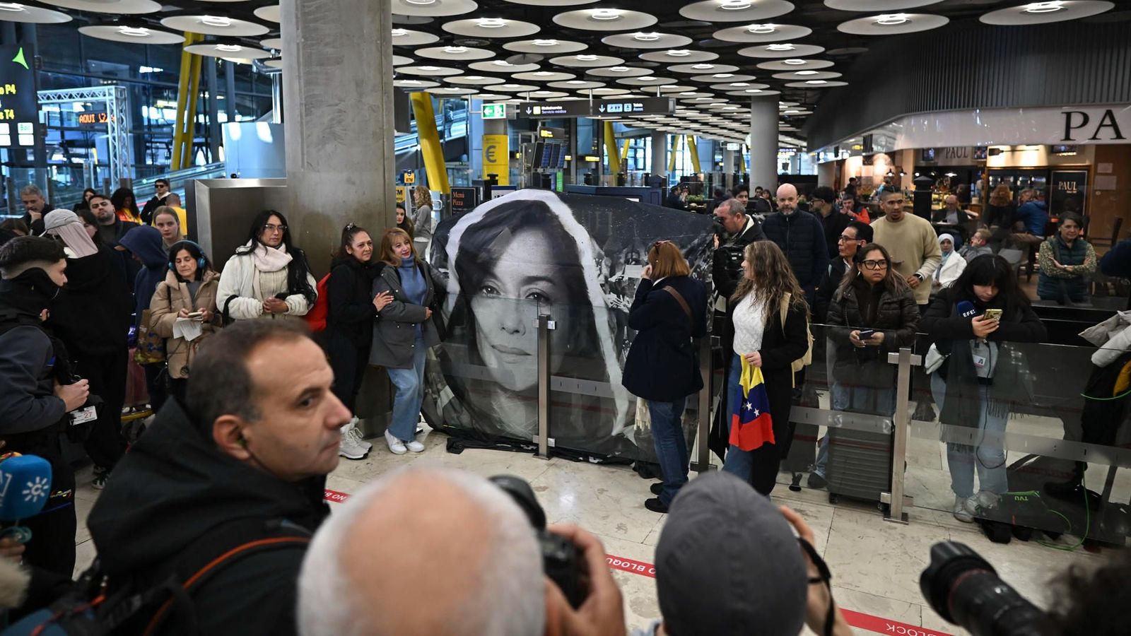 Un grup de persones sosté una pancarta amb la foto de Rocío San Miguel en l'Aeroport Adolfo Suárez Madrid Barajas