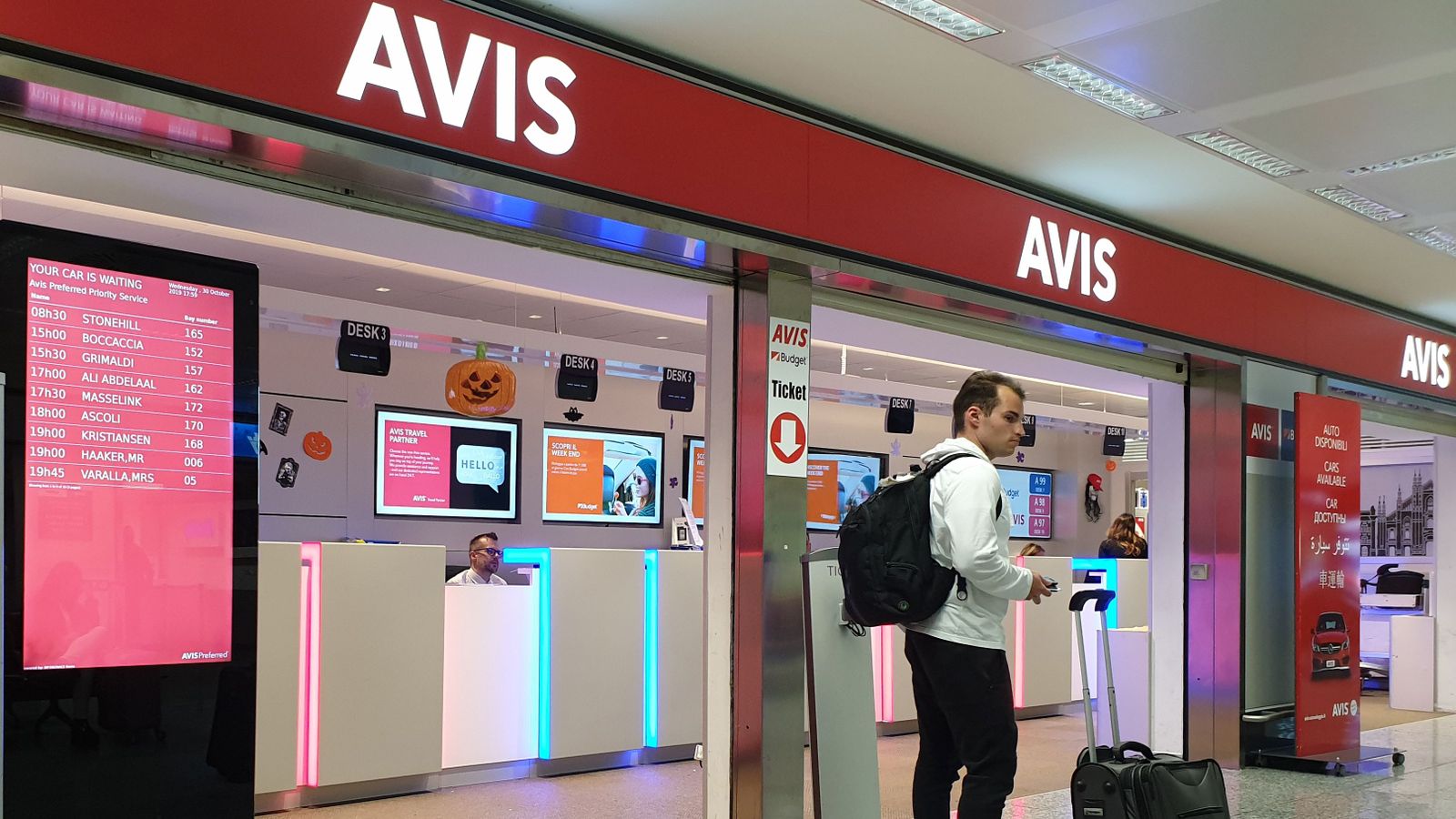 Un viatger passa per davant d'una oficina d'AVIS en un aeroport internacional