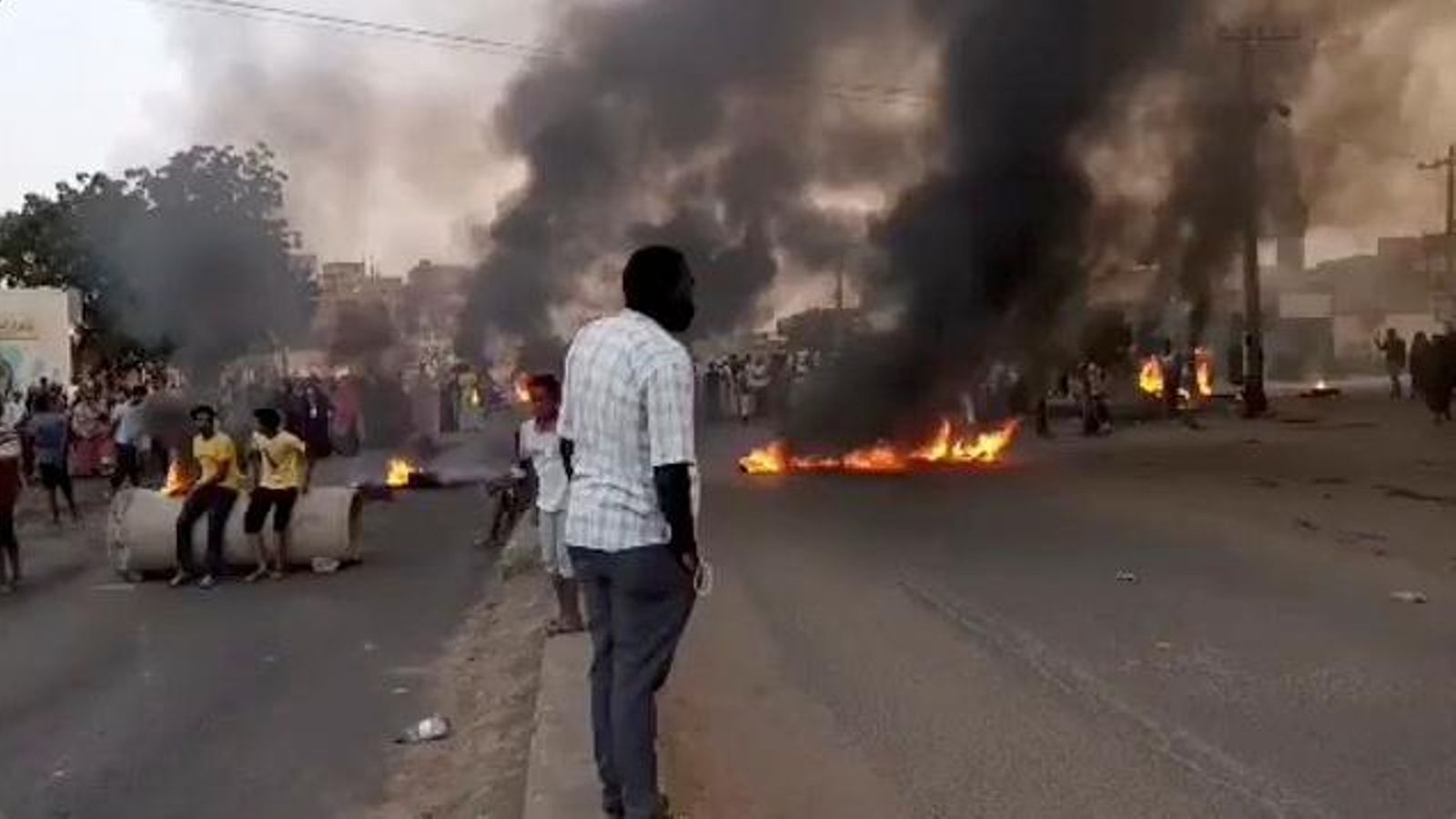 Diverses persones en el carrer de Khartum, la capital del Sudan, on ja es veuen pneumàtics cremats