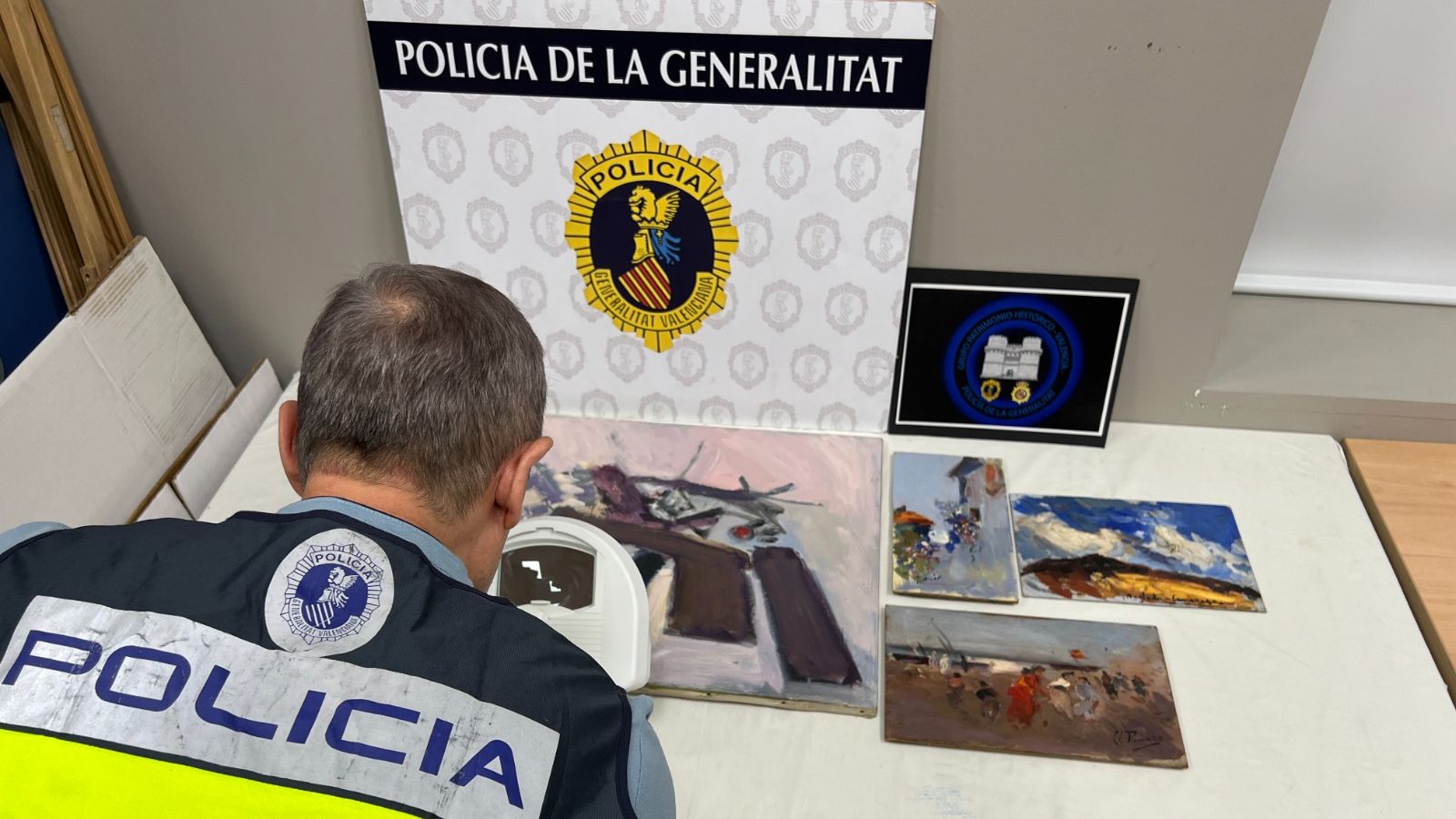 Un agent de la Policia de la Generalitat inspecciona les pintures confiscades