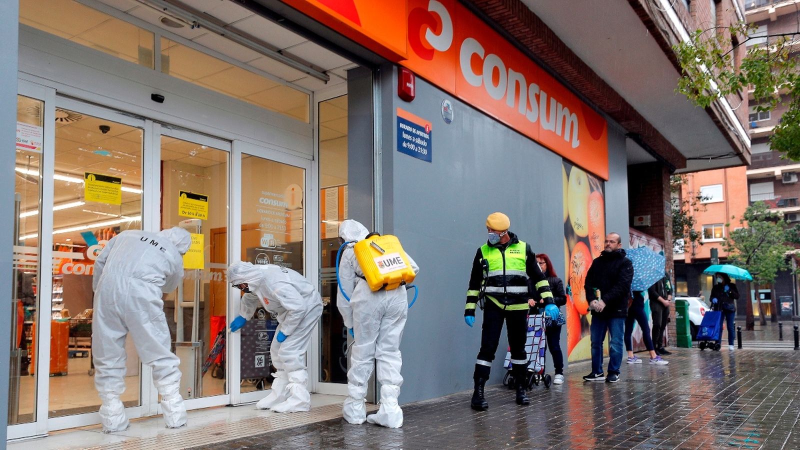 Membres de l'UME fan treballs de desinfecció a la porta d'un supermercat