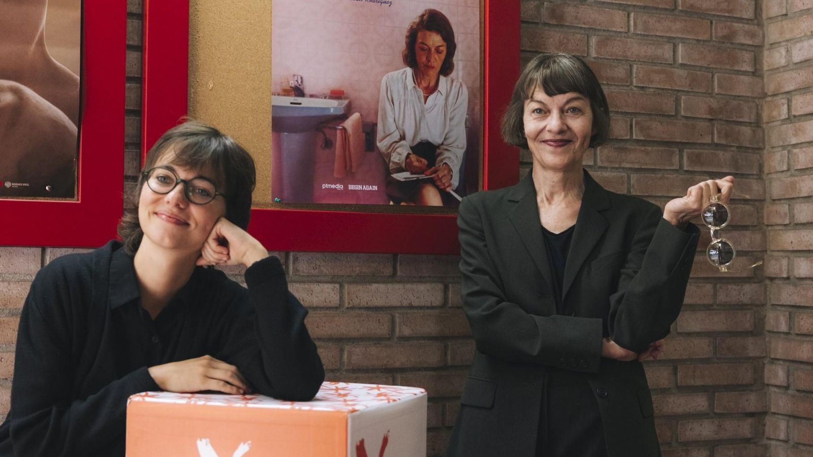 Lucía Casañ i Nüria González davant en el cartell d'Un bany propi' als cines Babel