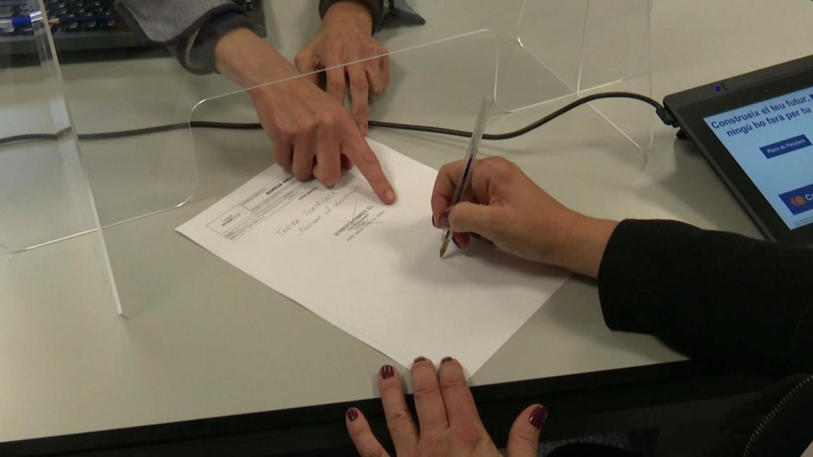 Una clienta firma un document bancari per a la hipoteca.