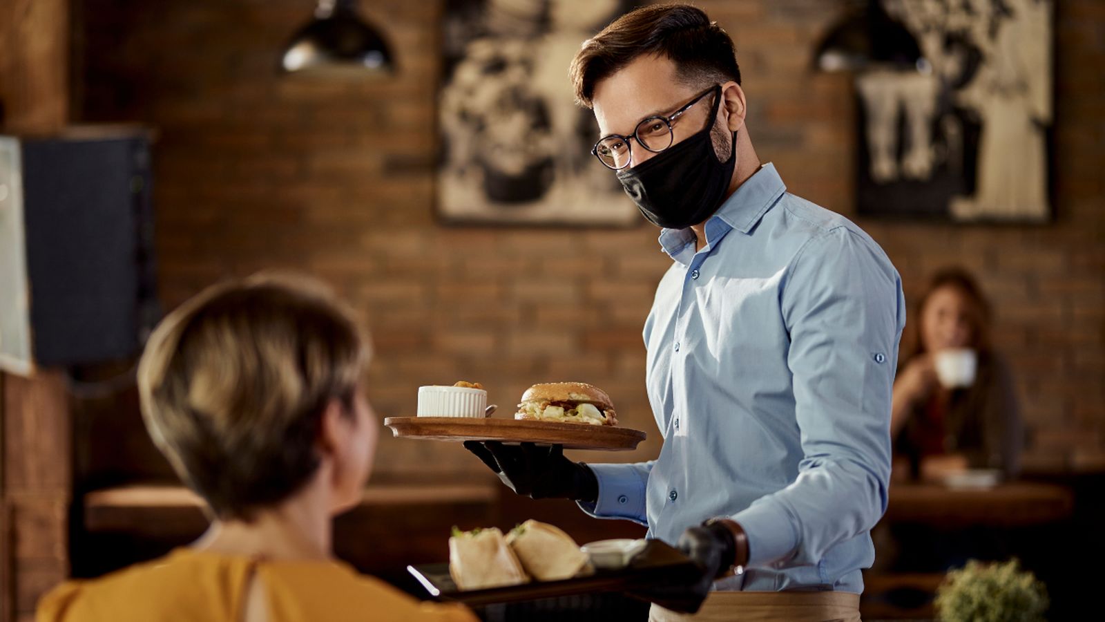 Un cambrer atén a una clienta en un restaurant