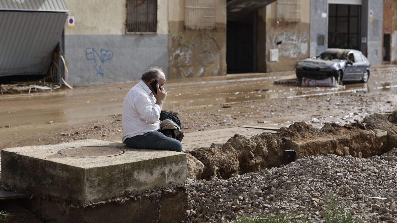 Un home parla per telèfon en una de les zones de València afectades després de les intenses pluges