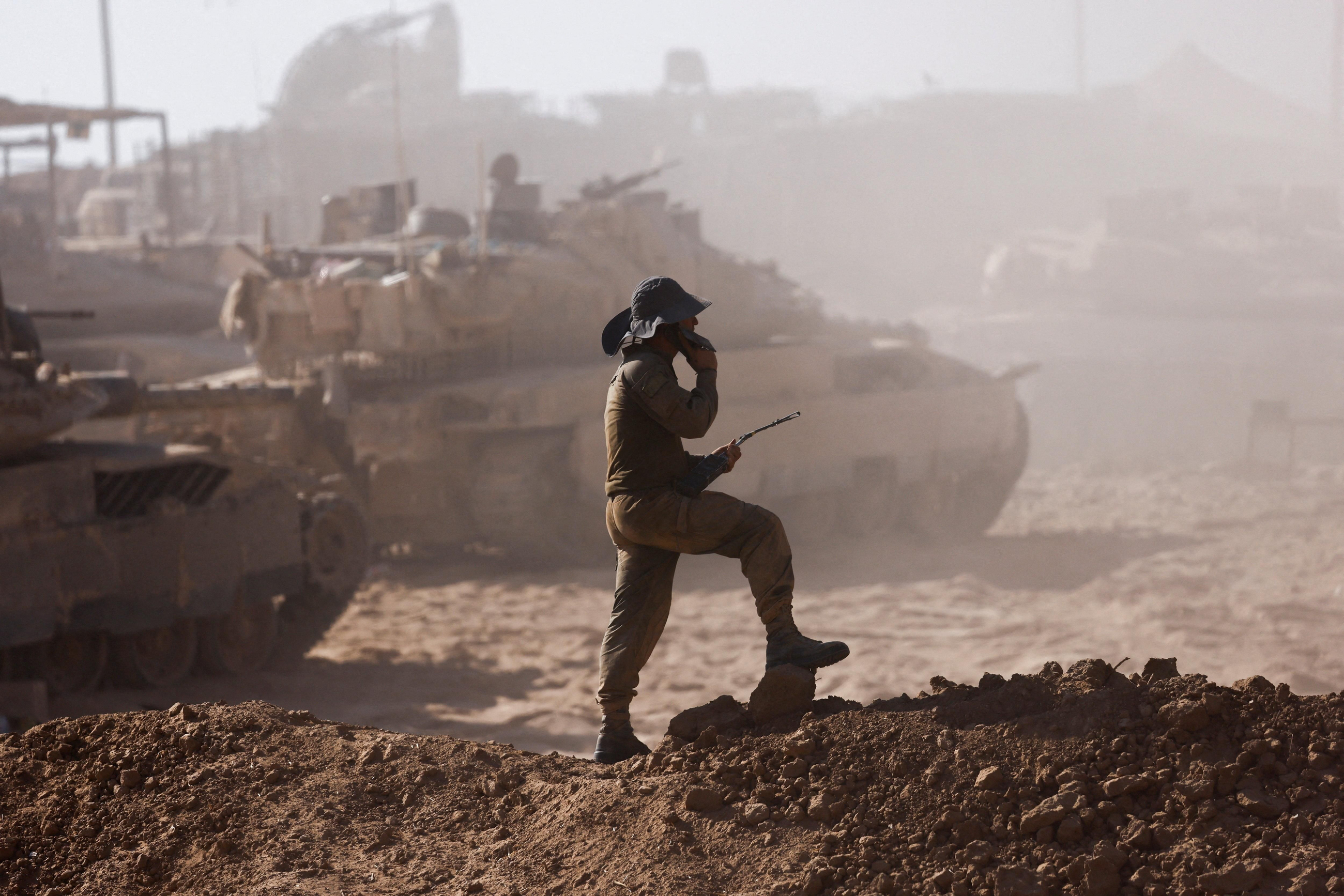 Un soldat israelià al costat de vehicles militars vist des del costat israelià de la frontera entre Israel i Gaza. Un soldat israelià al costat de vehicles militars vist des del costat israelià de la frontera entre Israel i Gaza.