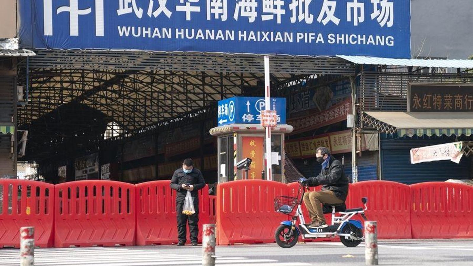 Dos ciutadans passen per l'entrada del mercat de mariscos Huanan a Wuhan, província de Hubei, el passat 29 de gener