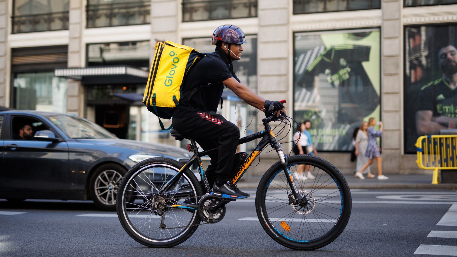 Un repartidor de Glovo amb bicicleta per un carrer en una imatge d'arxiu