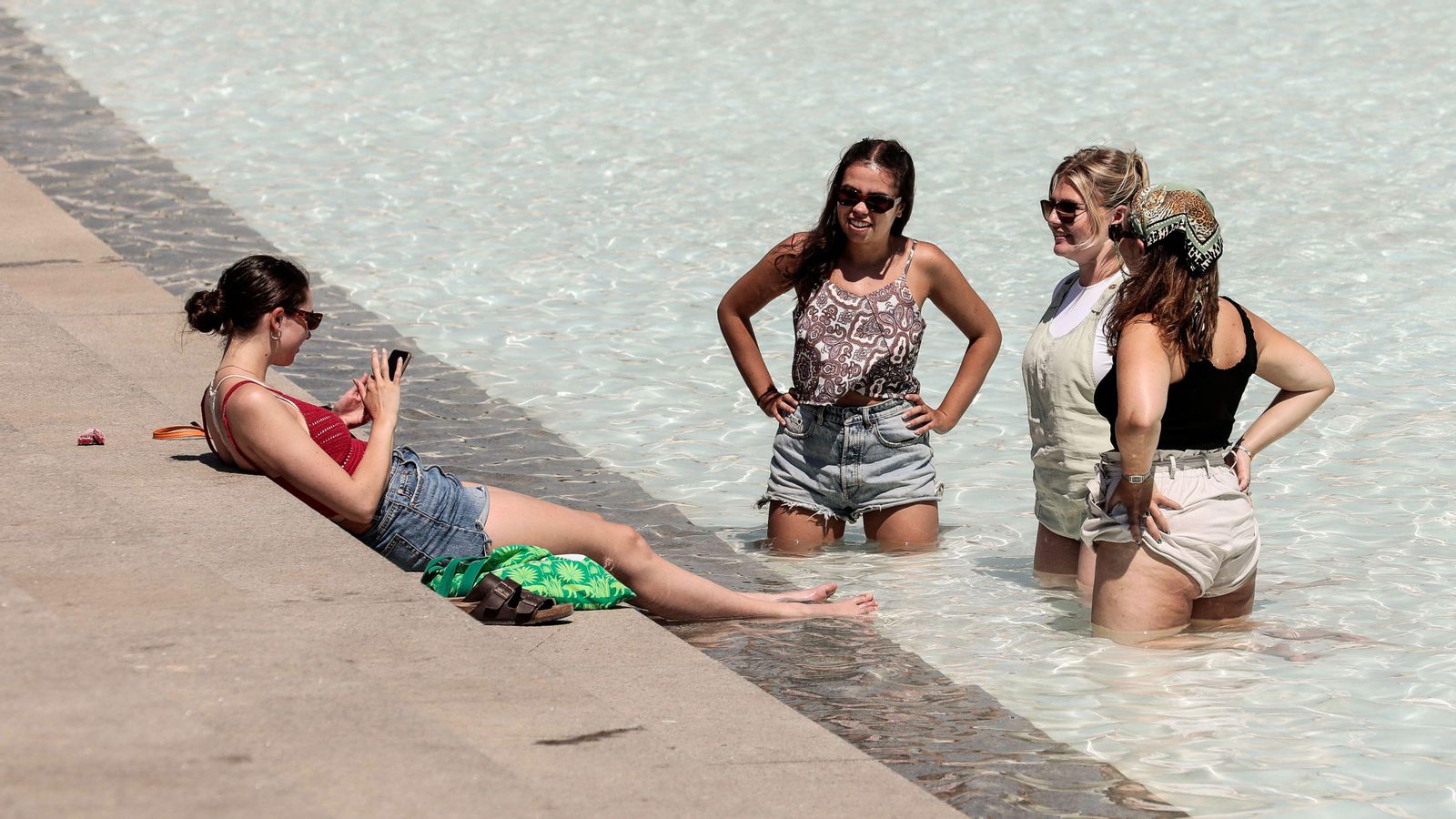 Quatre joves es refresquen en la zona d'aigua de la Ciutat de les Arts de València