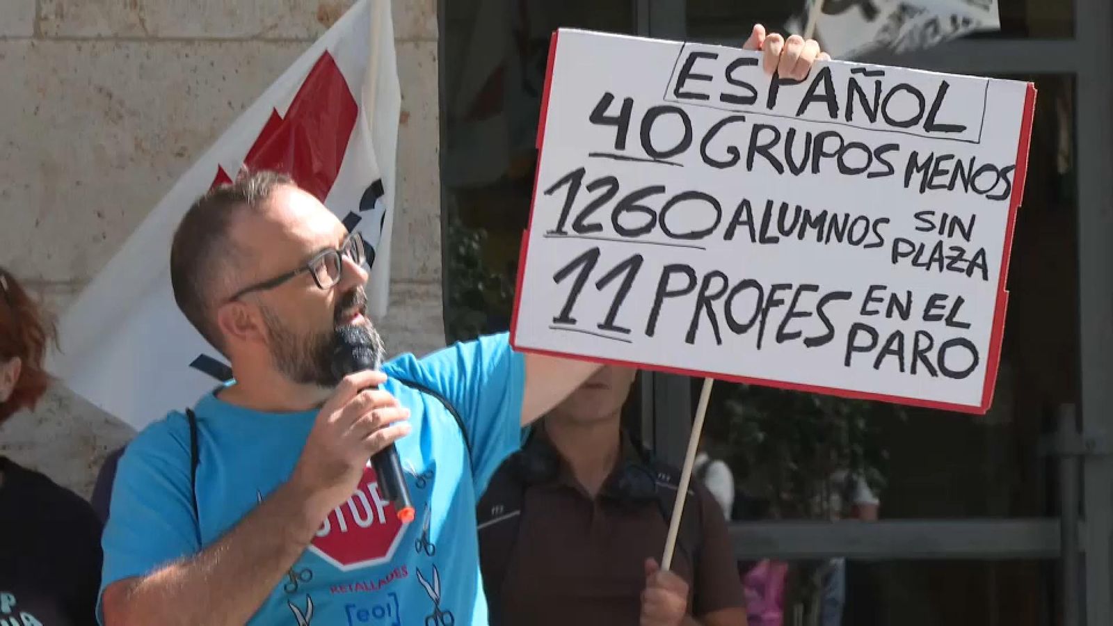 Un dels docents afectats mostra una pancarta amb les retallades durant la protesta