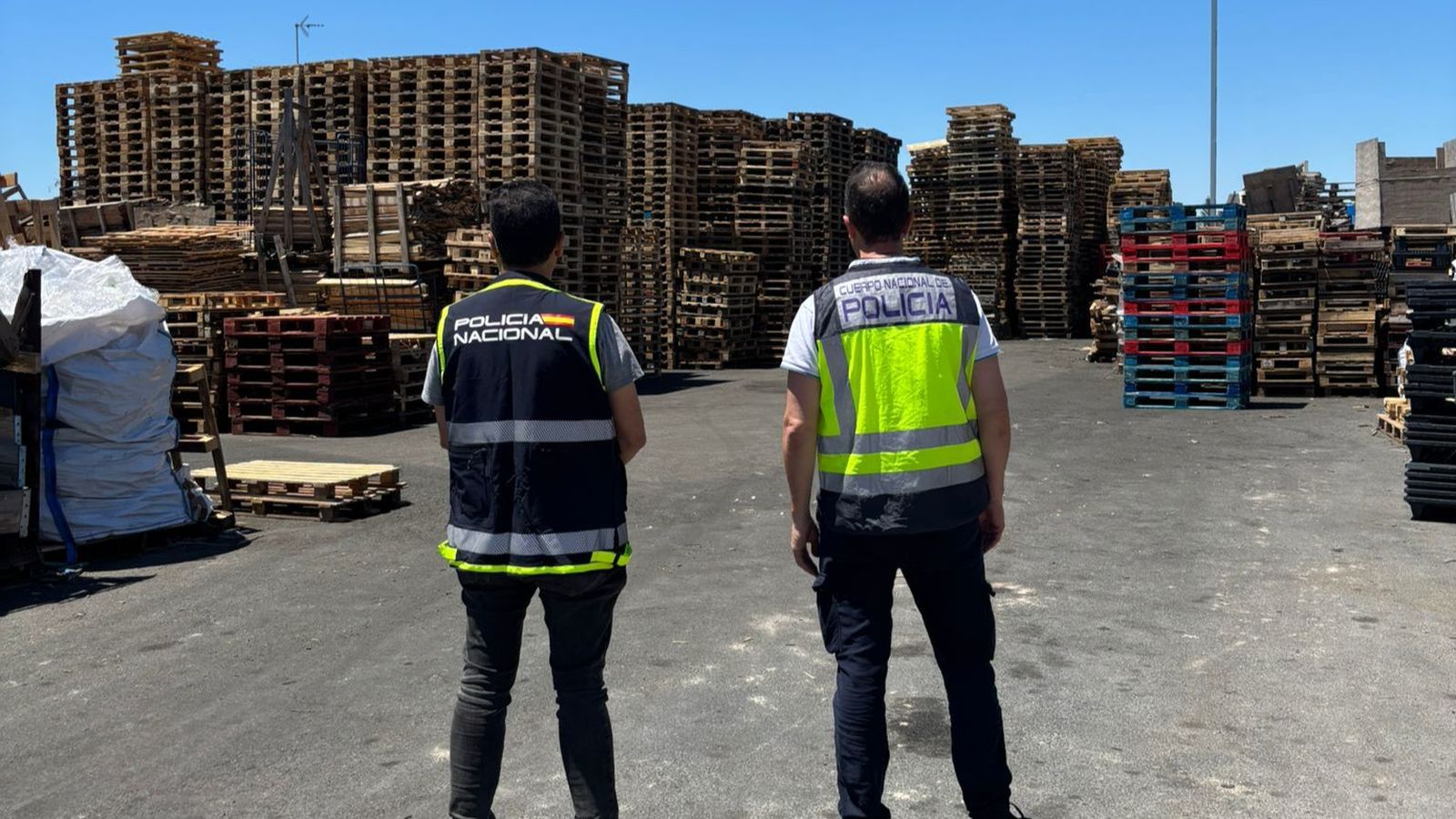 Dos agents de la Policia Nacional observen les piles de palets, elements que van usar els investigats per a estafar l'empresa del primer