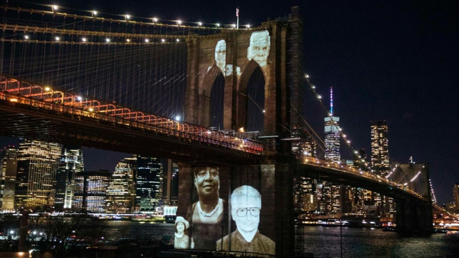 Imatges de persones que van morir per complicacions relacionades amb la malaltia covid-19 van ser projectades aquest diumenge sobre el Pont de Brooklyn. / Kevin Hagen (Efe)