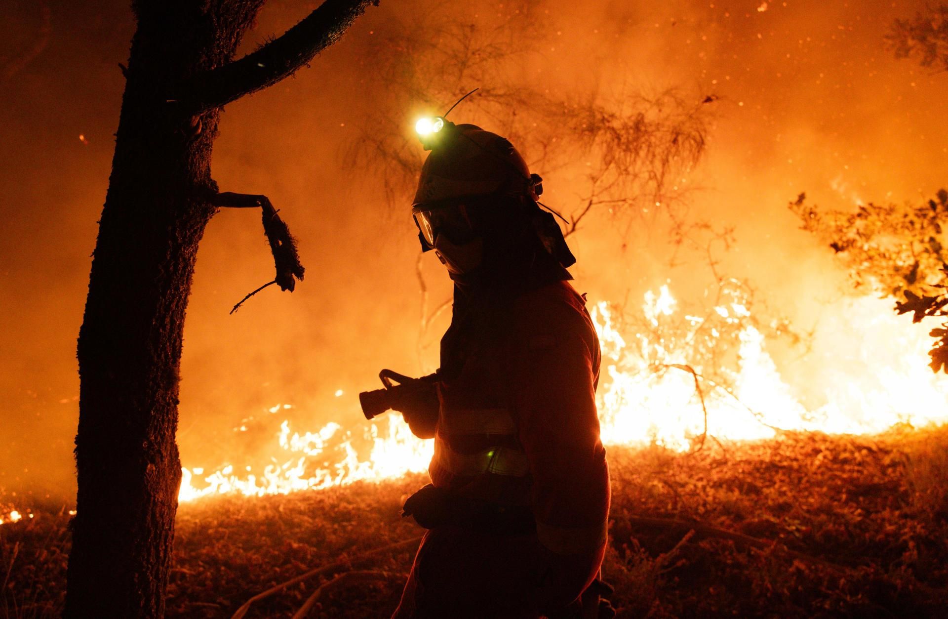Un bomber lluita contra el foc a Oimbra, Ourense