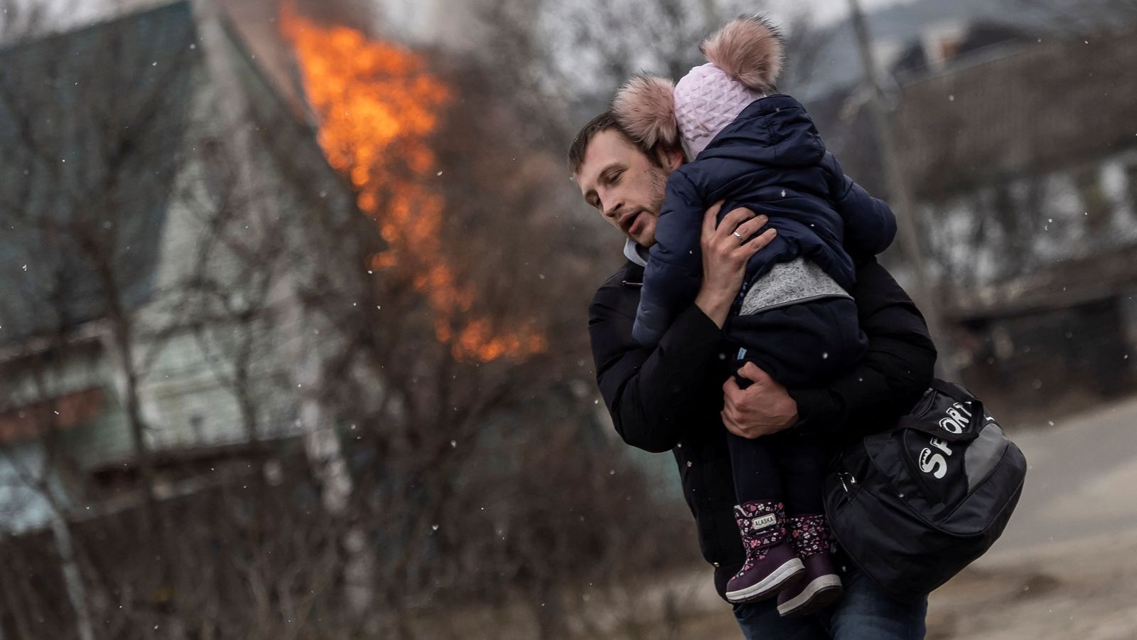 Un home fuig amb una criatura de pocs anys de la ciutat d'Irpin, prop de Kíiv, aquest diumenge