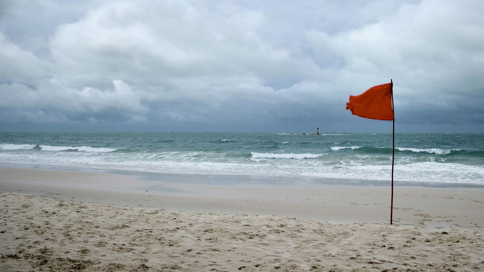 La mar estarà rebolicada des de les tres de la vesprada, amb ones de tres o quatre metres, segons les previsions d'Aemet Una bandera roja oneja en una platja