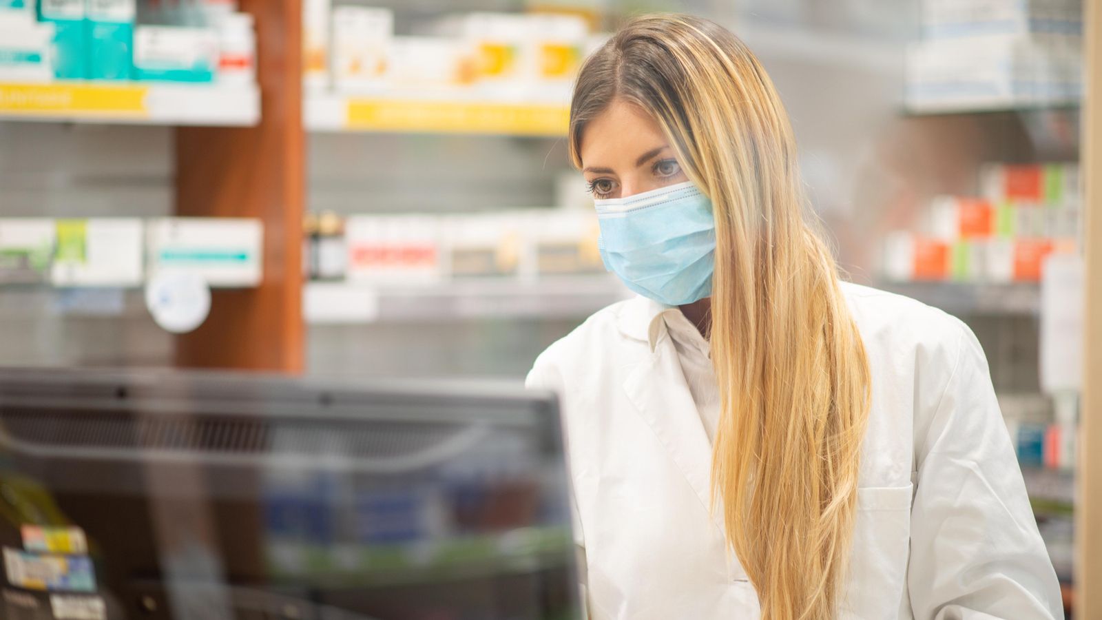 Una farmacèutica, que treballa amb la mascareta posada Una farmacèutica treballant amb la mascareta posada