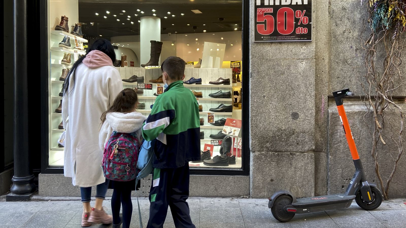Diverses persones en l'aparador d'un comerç que anuncia descomptes del 50% pel Black Friday