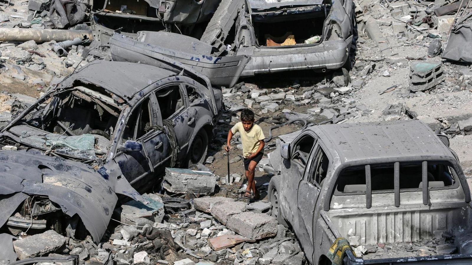 Un xiquet camina entre cotxes calcinats pels bombardejos israelians a la franja de Gaza