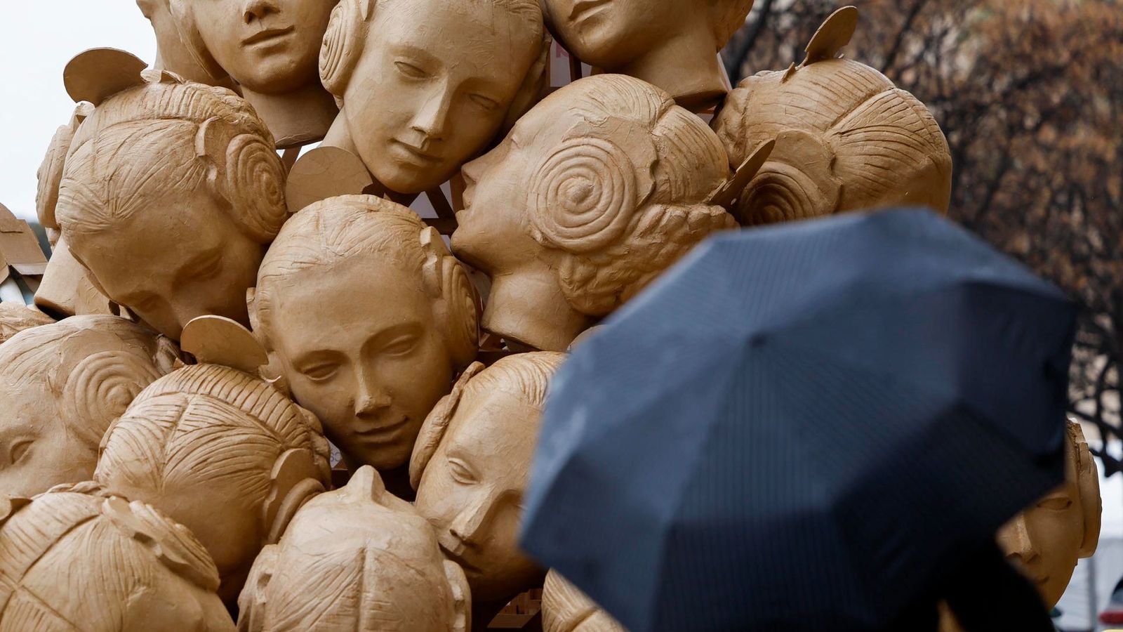 Un vianant observa, amb paraigua, la falla Blanqueries, que enguany du per lema 'El pes de la tradició' de València