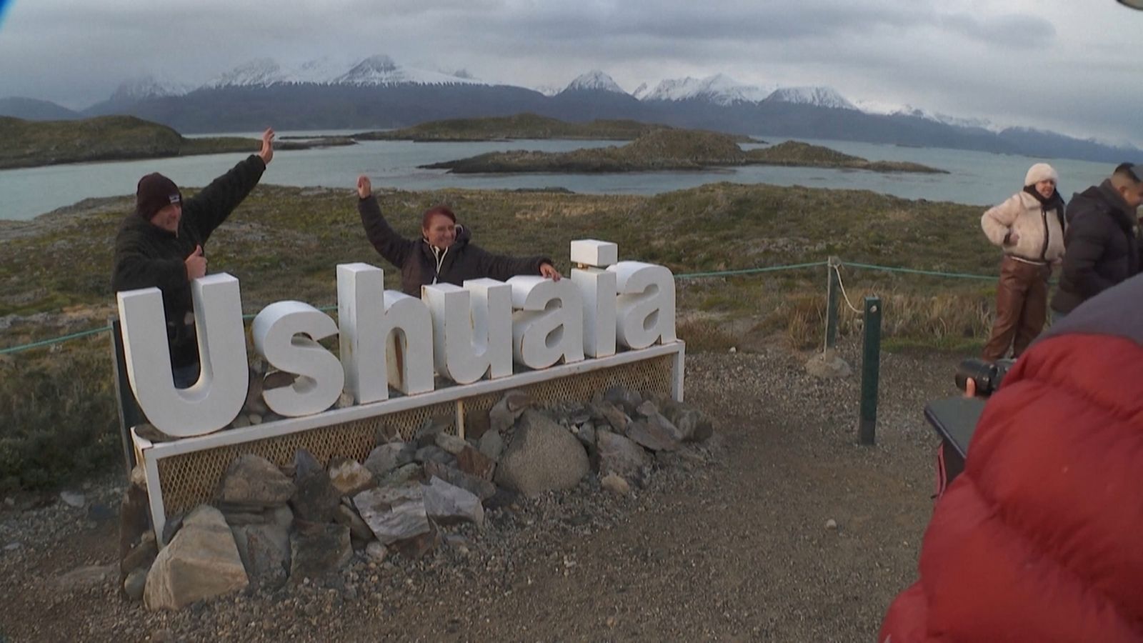 Cartell de la zona d'Ushuaia amb turistes