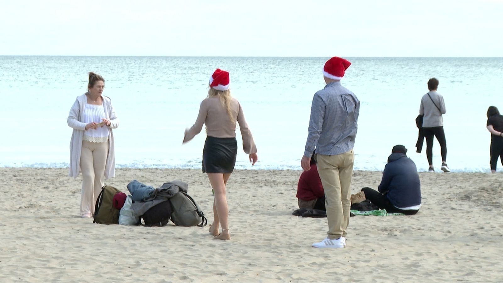 Diverses persones a la platja de la Malva-rosa amb barrets del Pare Noel