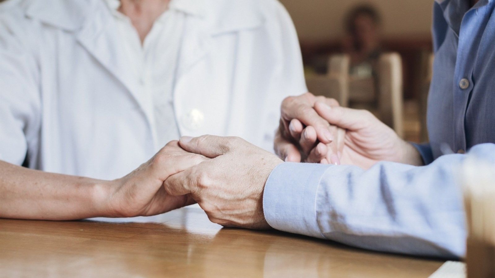 Un traballadora del sector social agafa la mà a un pacient, en arxiu