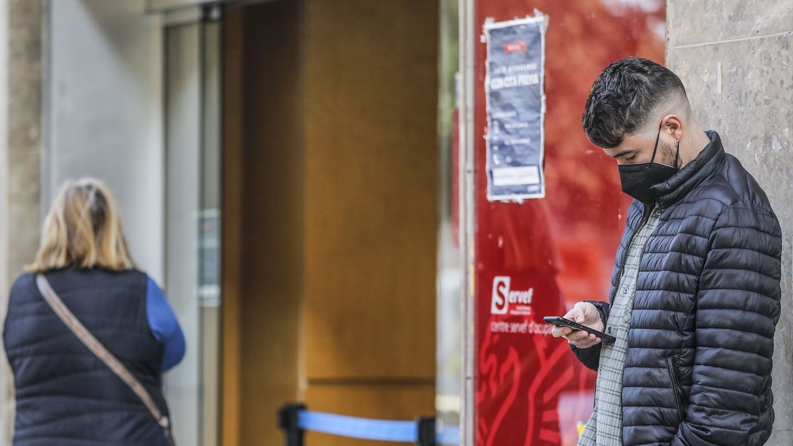 Diverses persones esperen per a entrar en una oficina de Labora (antic Servef) a València